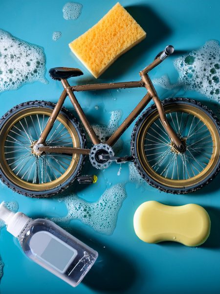 Realistische foto van een modderige fiets die omringt is met zeep water en spons